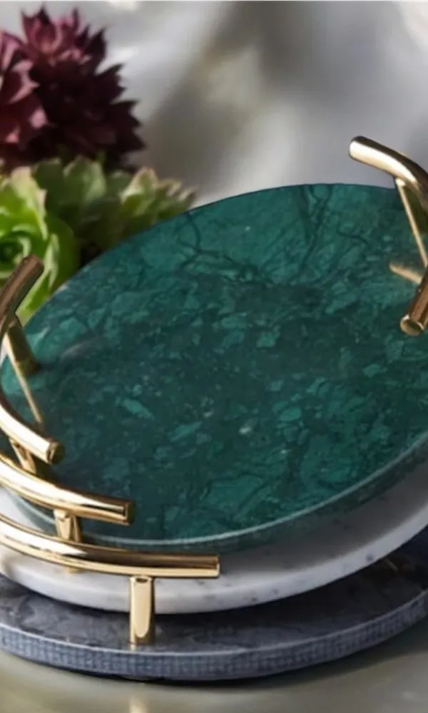 Round green marble tray with brass handles among succulents
